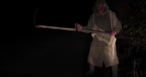 Zombie with a scythe moves at night along the road - Footage, Video