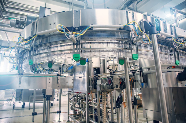 Equipo industrial automatizado del transportador de la máquina herramienta para embotellar el jugo en botellas plásticas en el interior de la fábrica de la bebida
 - Foto, Imagen