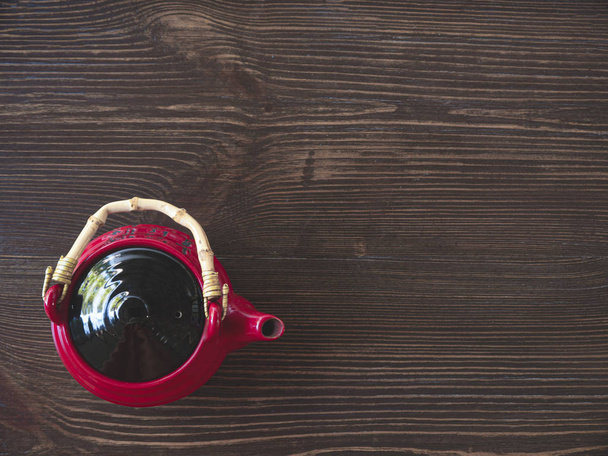 A piros kínai teáskanna egy fából készült asztal. A nézet felülnézete - Fotó, kép