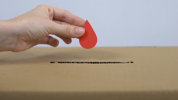 Mano femminile mettendo segno di goccia rossa nella scatola di cartone, centro di donazione di sangue, aiuto
 - Filmati, video