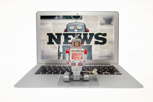 retro robot néz hamis híreket a laptopon  - Fotó, kép