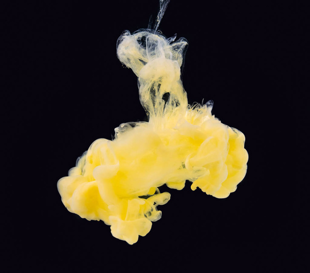 Acrylic paint in water isolated on black background, close up view. Yellow-white ink swirling under water, abstract black background. Ready to use blending mode to screen or add. - Фото, изображение