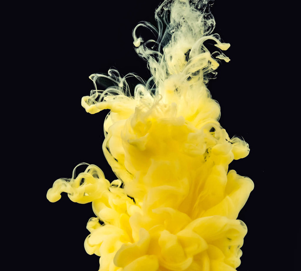 Yellow-white acrylic smoke mixing with water, isolated on black background, close up view. Drop of ink mixing with liquid. Abstract black background for overlays design, screen blending mode layer. - Foto, imagen