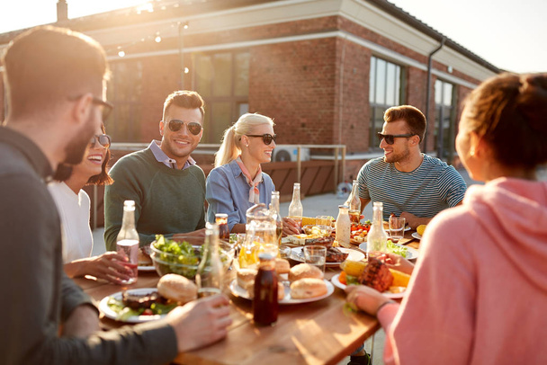 friends having dinner or bbq party on rooftop - Foto, imagen