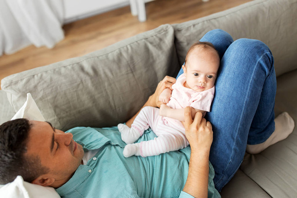 middle aged father with baby lying on sofa at home - Fotoğraf, Görsel
