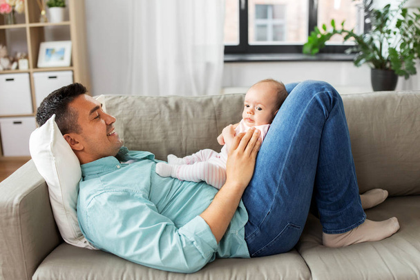 middle aged father with baby lying on sofa at home - Foto, Imagen