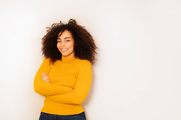 Happy young student age black girl with curly hair big smile and crossed hands over white wall - Foto, Bild