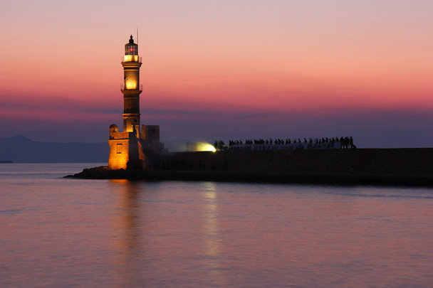 Zobacz latarnia morska przez zachód słońca w weneckiego portu chania, Kreta, Grecja - Zdjęcie, obraz