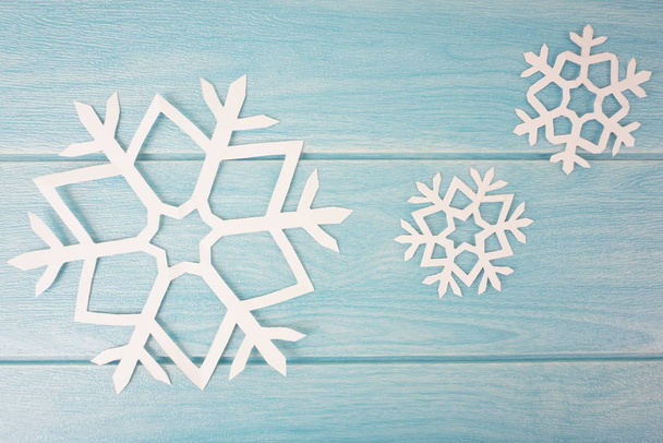 origami paper snowflakes on blue wooden table surface, top view  - Foto, Bild