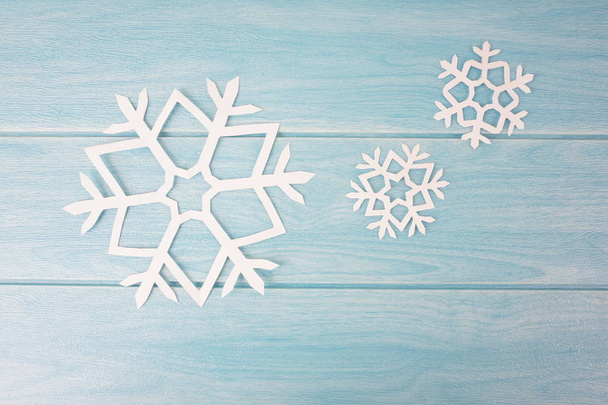 origami paper snowflakes on blue wooden table surface, top view  - Fotografie, Obrázek
