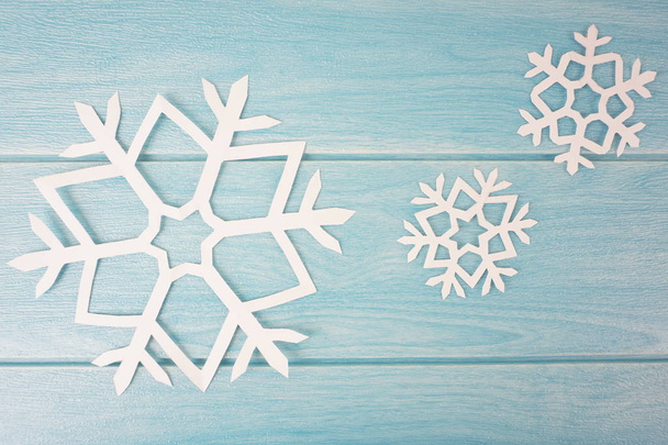 Origami papieru płatki śniegu na niebieskim drewnianej powierzchni stołu, widok z góry  - Zdjęcie, obraz