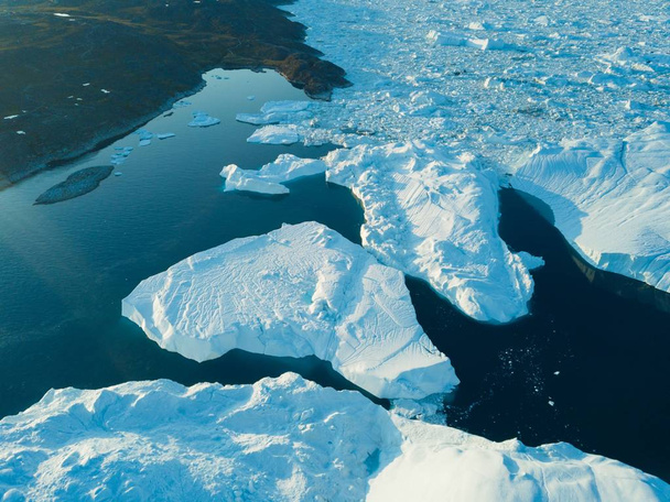 Изображение сверху с беспилотного летательного аппарата - Изменение климата и глобальное потепление. Айсберги от таяния ледника в леднике в Илулиссате, Гренландия. Ледовый ландшафт Арктики в объекте Всемирного наследия ЮНЕСКО - Фото, изображение