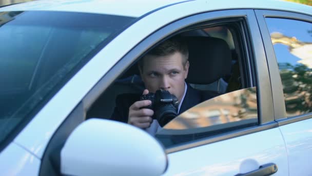 Private detective spying from car, taking photos on camera, investigation - Záběry, video