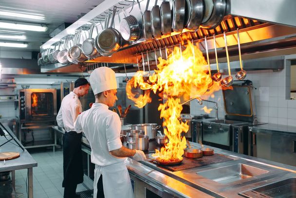 Modern kitchen. Cooks prepare meals on the stove in the kitchen of the restaurant or hotel. The fire in the kitchen. - Foto, Imagem