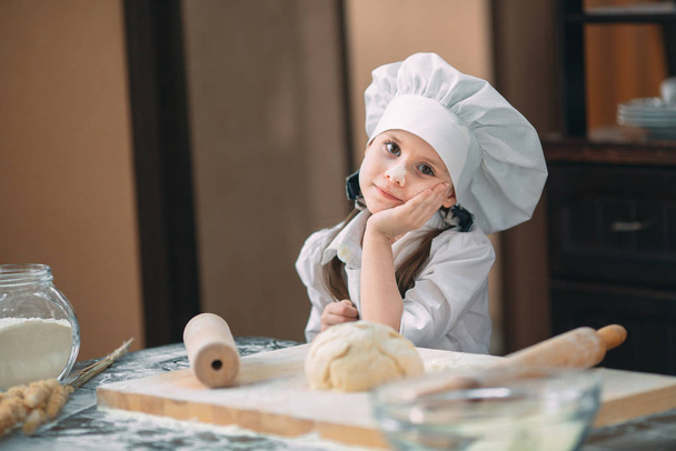 girl kid are preparing the dough in the kitchen. - Фото, зображення