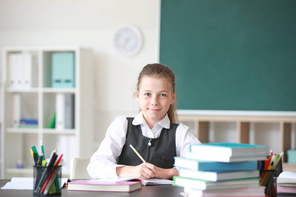 Cute little schoolgirl doing lessons in classroom - Fotografie, Obrázek