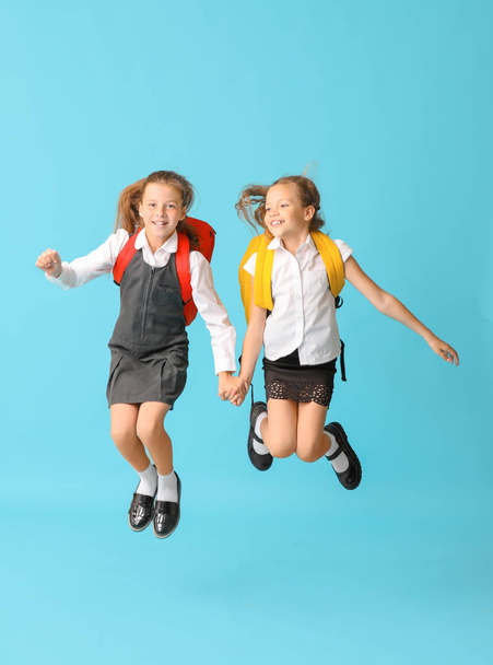 Cute jumping schoolgirls on color background - Photo, Image