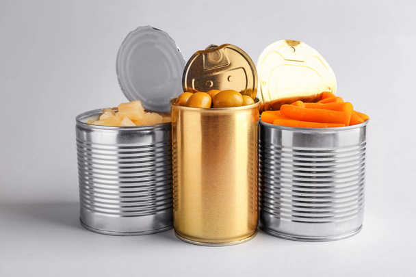 жестяные банки с различными продуктами питания на светлом фоне
 - Фото, изображение