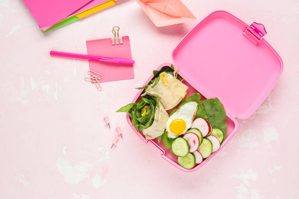School lunch box with tasty food and stationery on light background - Foto, Imagem