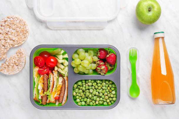 School lunch box with tasty food and juice on light background - Photo, Image