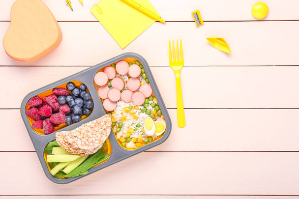 Boîte à lunch scolaire avec une nourriture savoureuse et de la papeterie sur la table
 - Photo, image