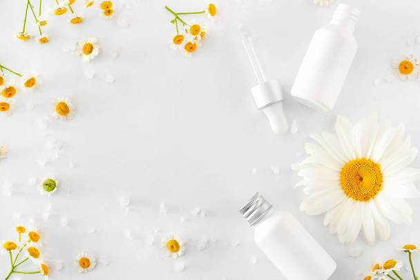 Marco de productos cosméticos con flores de manzanilla sobre fondo blanco
 - Foto, imagen
