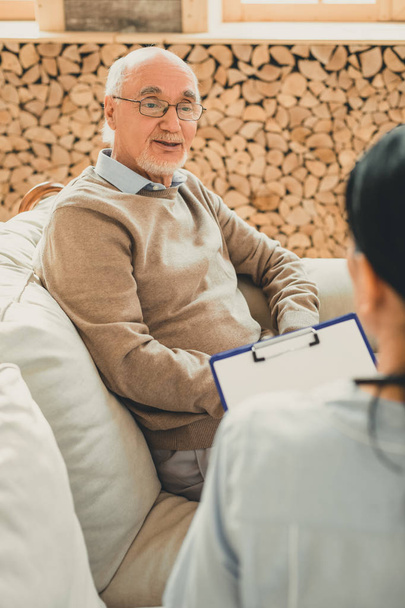 Smiling senior in brown sweater during doctor appointment - 写真・画像