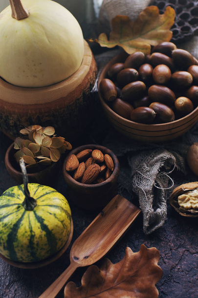 Fondo autunnale con zucca decorativa, mais, noci, foglie autunnali, ghiande sul tavolo di pietra scura
 - Foto, immagini
