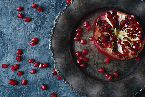 Fresh organic juicy pomegranate on a silver plate on dark stone background, healthy lifestyle concept - Foto, Imagem