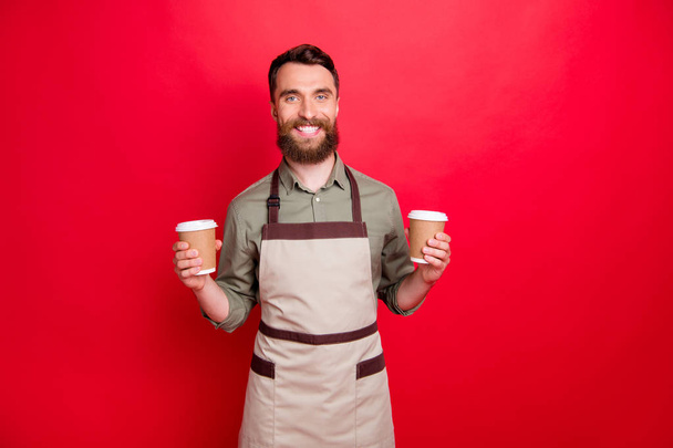 Portrait of his he nice attractive cheerful cheery content bearded guy waiter holding in hands cappuccino hot chocolate espresso isolated over bright vivid shine red background - Foto, Imagem