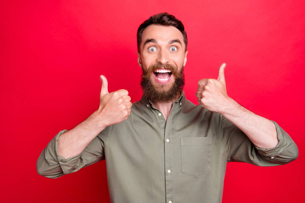 Photo of excited friendly overjoyed man being glad to have bought something while isolated with red background - Fotó, kép