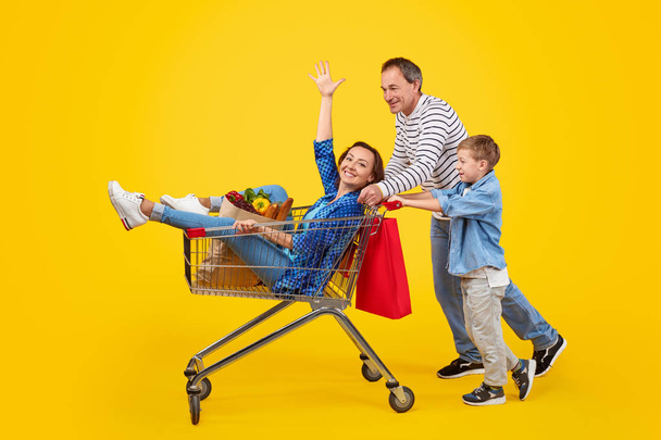 Happy family with trolley shopping together - Фото, изображение