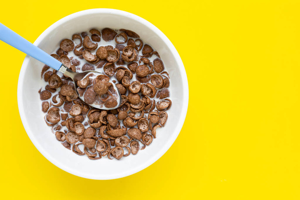 Chocolate cereal with milk on yellow background. - Foto, afbeelding