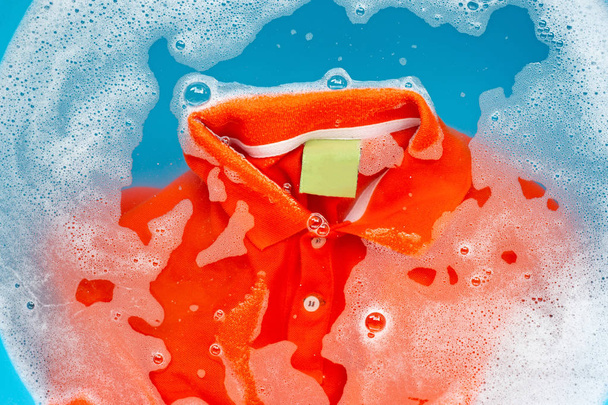 Orange polo shirt soak in powder detergent water dissolution, wa - Valokuva, kuva