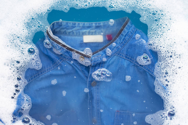 Camicia Jean immersa nella dissoluzione dell'acqua detergente in polvere. Lavanderia
 - Foto, immagini
