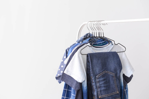 Стильний дитячий одяг, що висить на стійці на світлому фоні
 - Фото, зображення