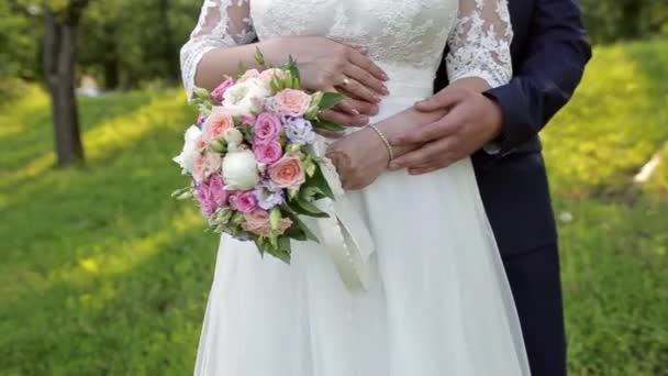 o noivo abraça a noiva, a noiva segura um buquê, a câmera se move ao nível do cinto e mostra o buquê de noivas e um anel de casamento em sua mão
 - Filmagem, Vídeo