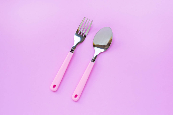 Tenedor y cuchara sobre fondo rosa
. - Foto, Imagen