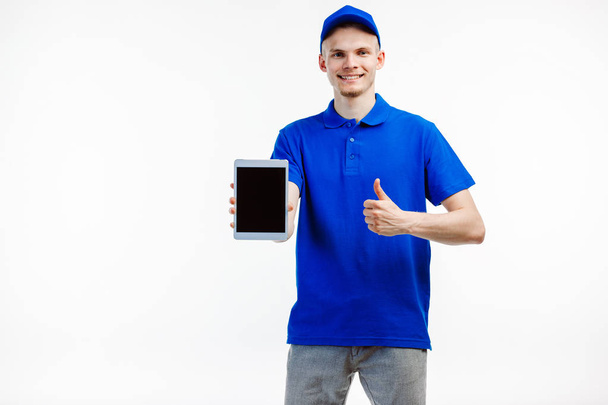 Young male courier holds a tablet turned off. - Foto, afbeelding