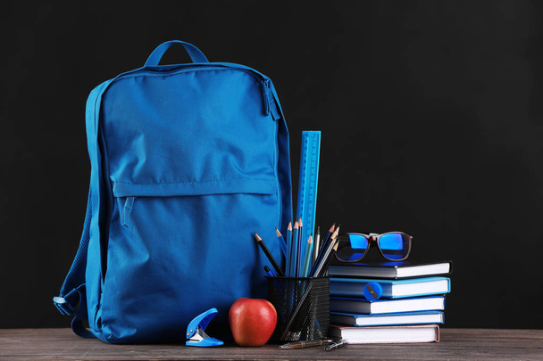 School backpack with stationery on table in classroom - Photo, Image