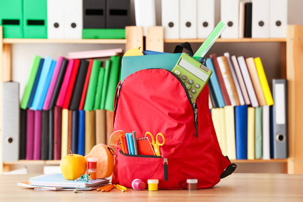 Рюкзак с канцелярскими принадлежностями на столе в классе - Фото, изображение