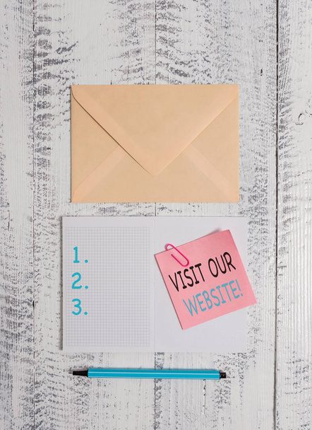 Writing note showing Visit Our Website. Business photo showcasing visitor who arrives at web site and proceeds to browse Envelop squared notepad note clip marker old wooden vintage background. - Photo, Image