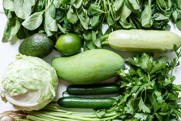 Fresh green vegetables variety on rustic white background from overhead, celery, avocado, cabbage, mango, cucumber, spinach, lime, squash. Healthy, vegetarian concept. Flat lay, top view - Foto, imagen