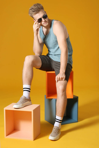 Stylish young man in sportswear on color background - Fotoğraf, Görsel