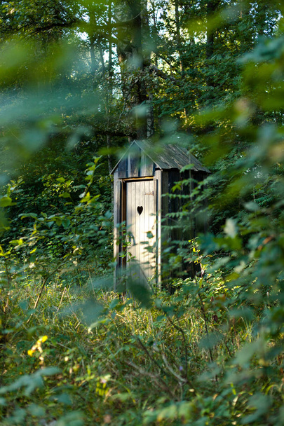 Kehystetty näkymä yksityinen ulkona puinen wc sydämen muotoinen metsässä
 - Valokuva, kuva