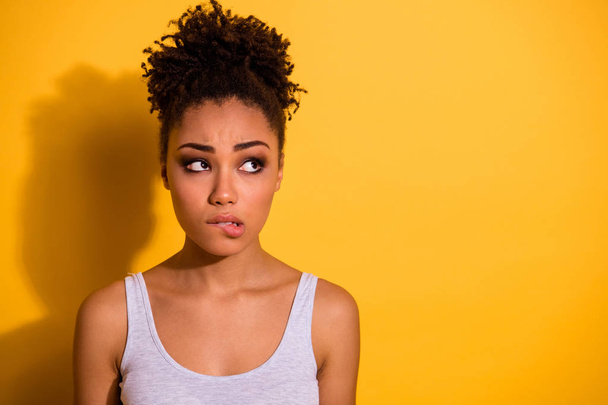 Close up photo beautiful amazing she her dark skin lady look not smiling empty space oops I did it again facial expression bite lip feel guilty wear casual tank-top isolated vivid yellow background - Foto, Imagen