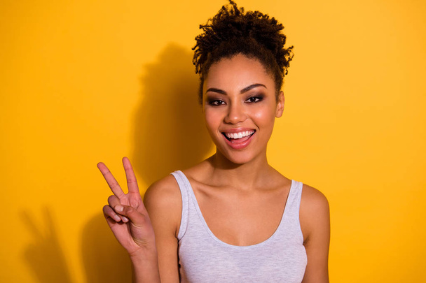 Close up photo beautiful amazing funny she her dark skin lady show white perfect ideal teeth carefree weekend vacation summer v-sign symbol wear casual tank-top isolated vivid yellow background - Foto, immagini