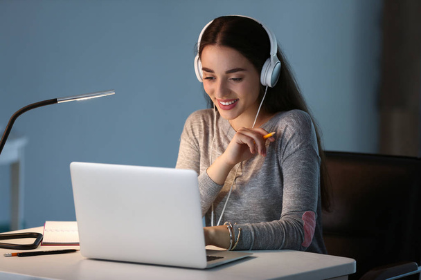 Студентка с ноутбуком, слушающая музыку во время подготовки к экзамену дома
 - Фото, изображение