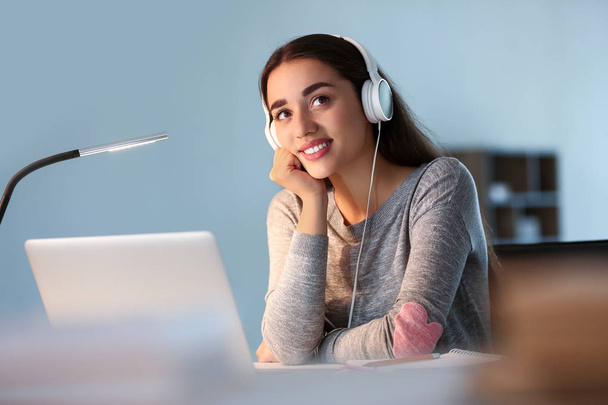 Studentessa con computer portatile che ascolta musica mentre si prepara per l'esame a casa
 - Foto, immagini