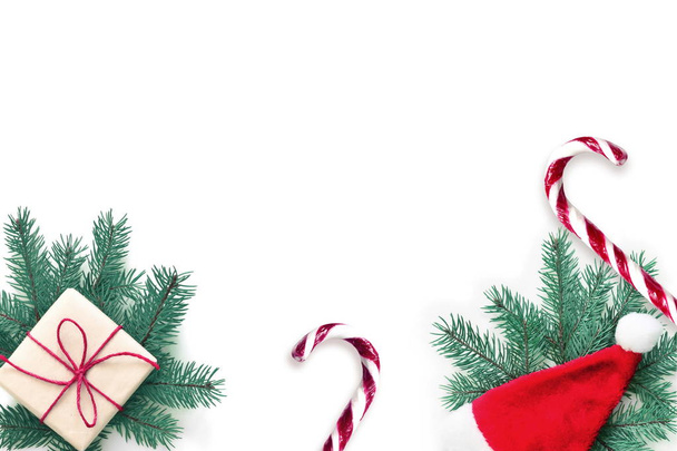Рождественская композиция Подарок, ель, Рождественская шляпа и сладкий костыль на белом фоне. Рождество, зима, новый год. Плоский, вид сверху
. - Фото, изображение